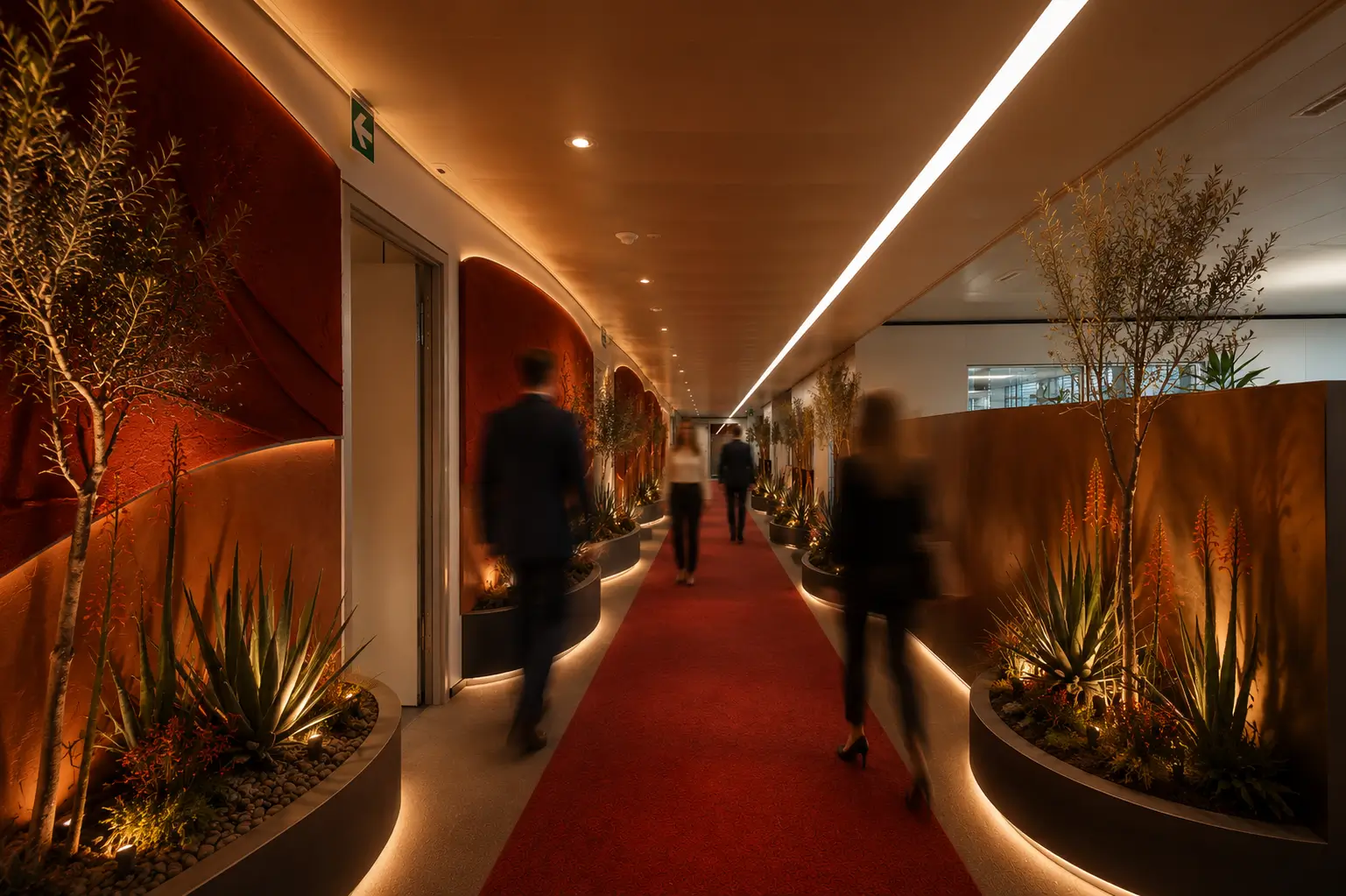 Warm terracotta corridor with red carpet, succulent-filled curved planters and people walking