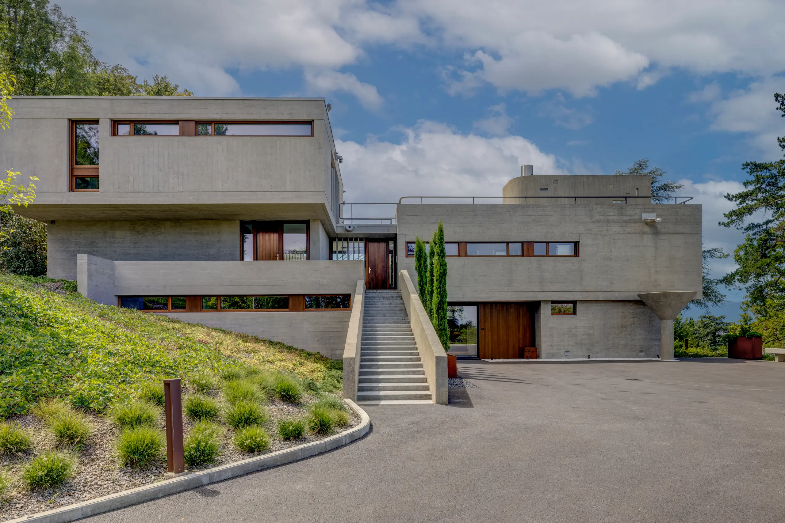Exterior of the listed 1958 villa — stacked concrete volumes with a planted green-roof terrace under a clear blue sky