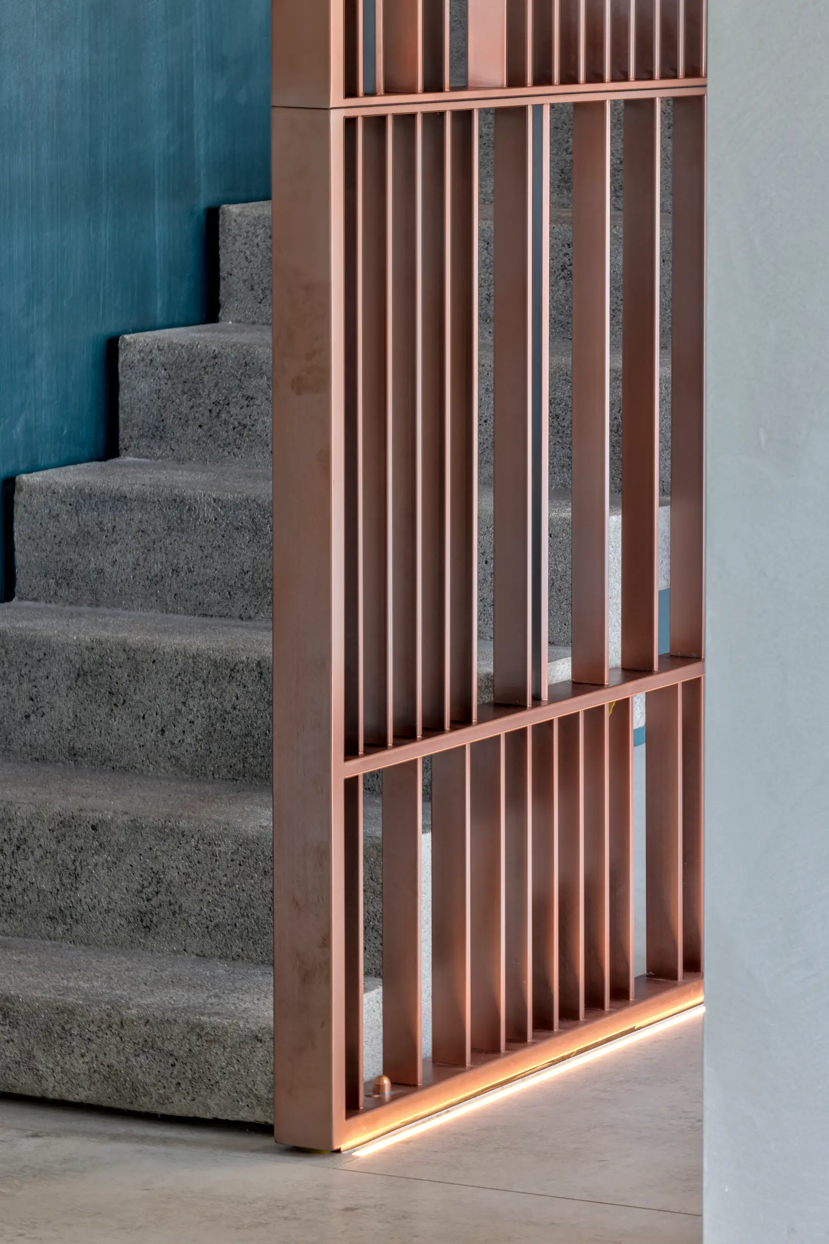 The preserved concrete staircase set behind a slatted copper-toned timber screen