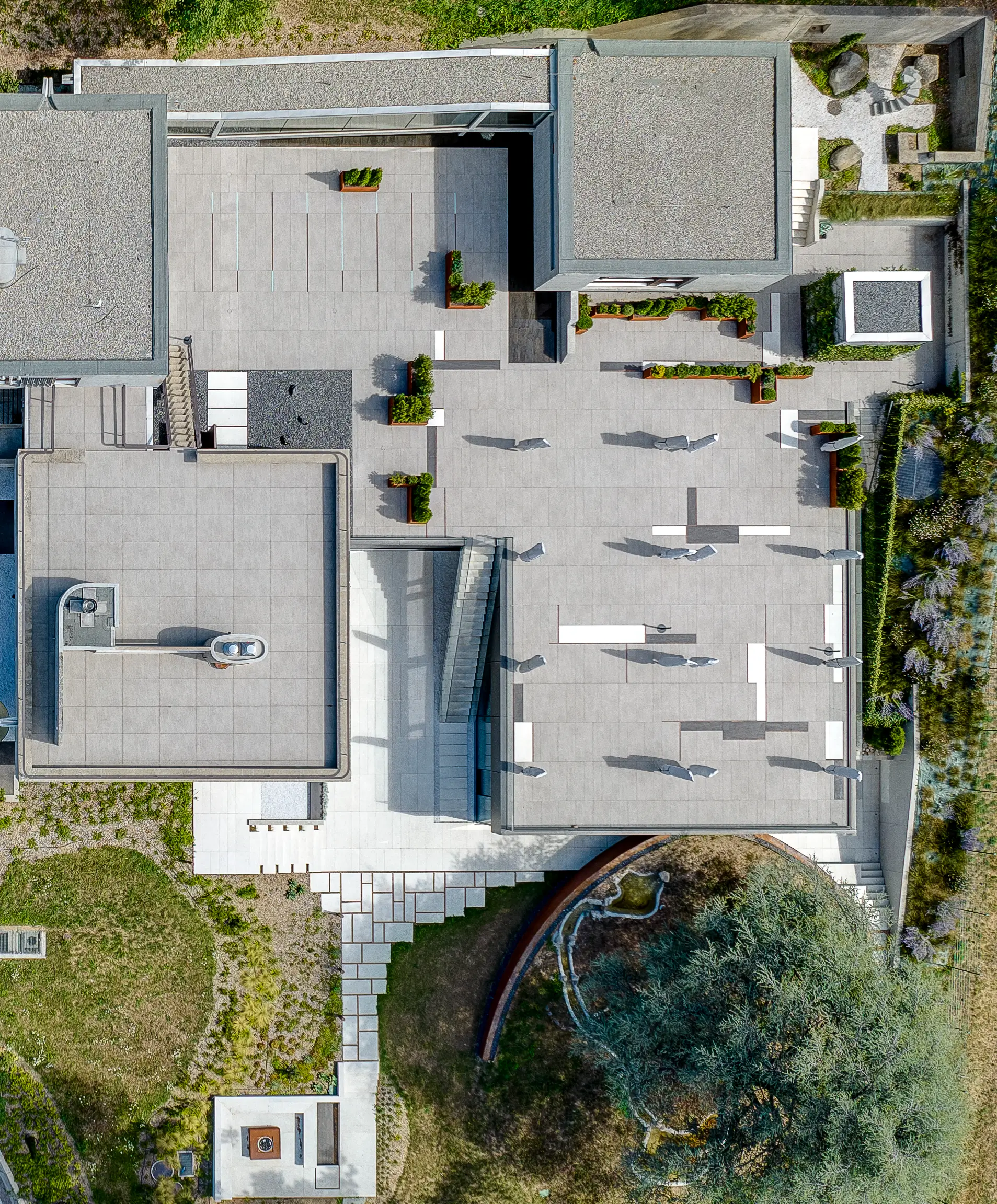 Aerial view of the villa’s terraced rooftops, paved courtyards and gardens stepping through the landscape