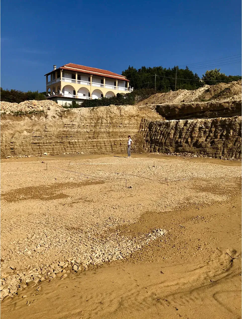 Construction phase: an excavated earthwork terrace cut into the coastal slope below the existing villa