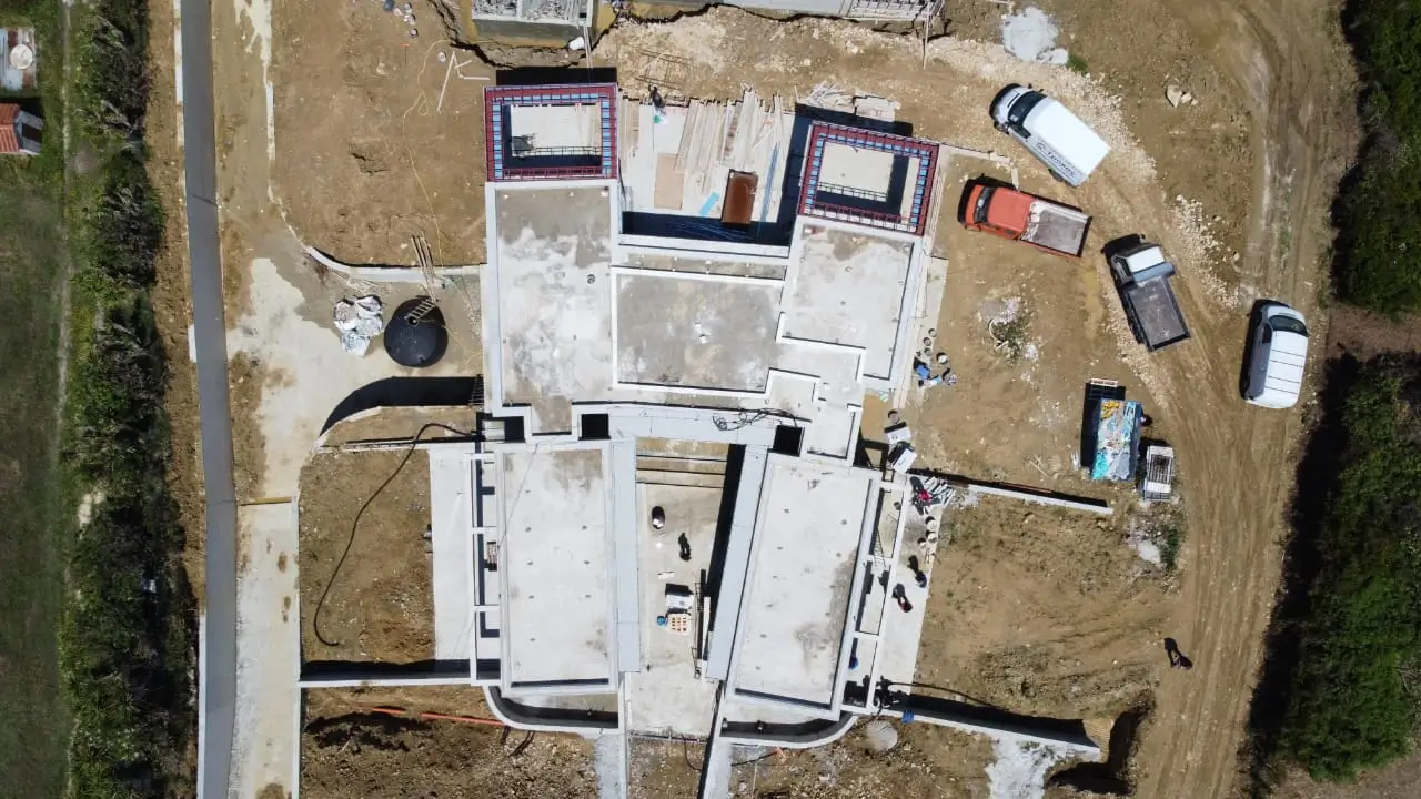Overhead construction view of the villa's poured concrete foundations and structural walls taking shape on site