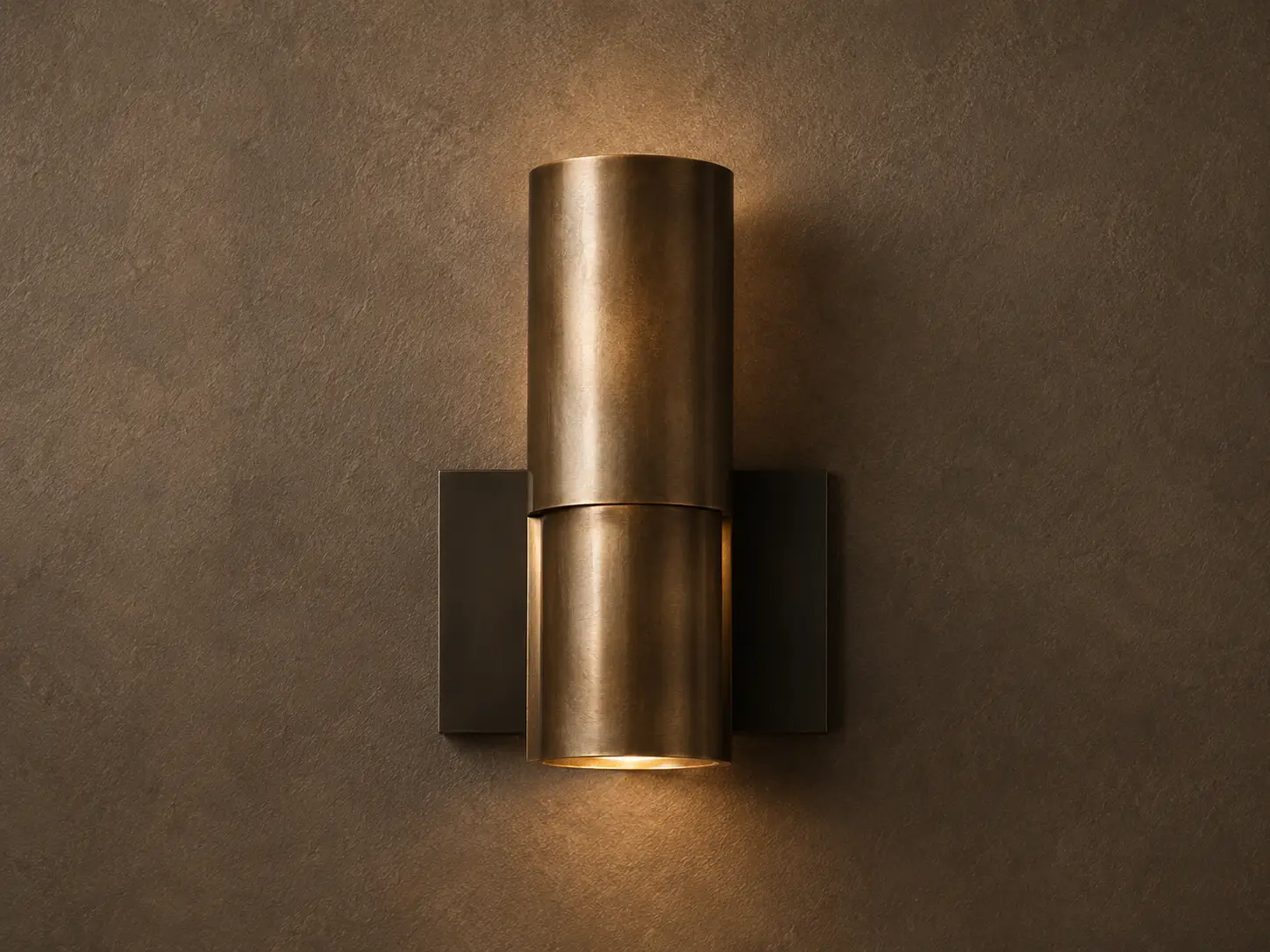 Brass wall sconce glowing against a textured plaster wall